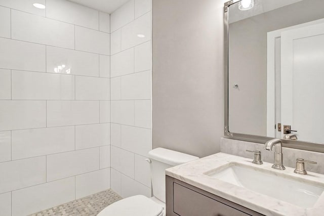 bathroom with vanity, toilet, and tiled shower