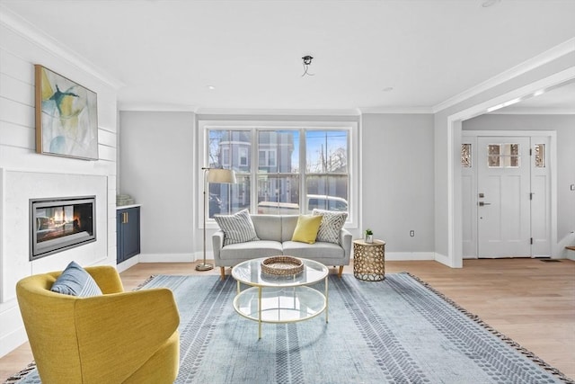 living room featuring a fireplace, ornamental molding, and light wood-type flooring