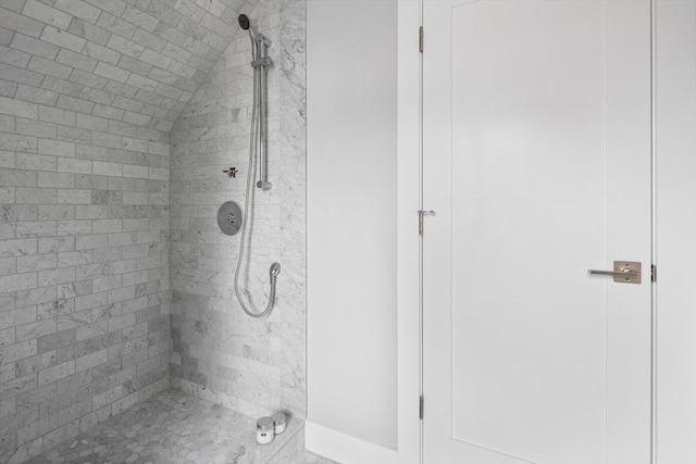 bathroom with vaulted ceiling and tiled shower