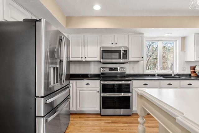 kitchen with white cabinetry, appliances with stainless steel finishes, light hardwood / wood-style floors, and sink