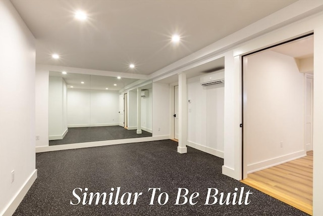 finished below grade area with an AC wall unit, baseboards, and recessed lighting