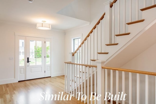 foyer entrance featuring stairway, baseboards, ornamental molding, and wood finished floors