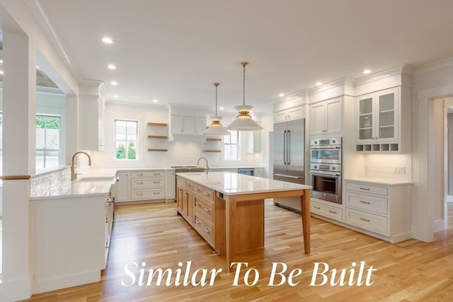 kitchen with open shelves, ornamental molding, light countertops, a sink, and stainless steel appliances