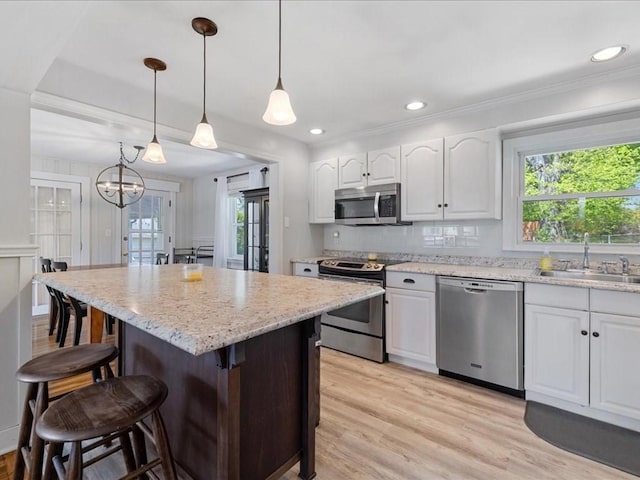 114 Hobart St, Braintree, MA 02184 - kitchen featuring light wood-style flooring, a kitchen bar, a sink, white cabinetry, and appliances with stainless steel finishes