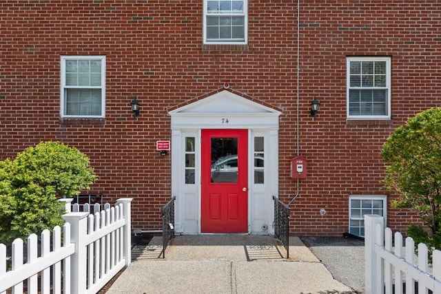property entrance with brick siding and fence