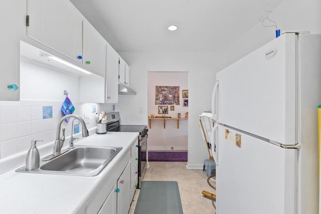 kitchen with freestanding refrigerator, stainless steel electric range, a sink, light countertops, and white cabinetry