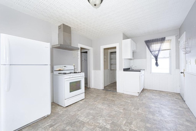 kitchen featuring white appliances, white cabinets, wainscoting, an ornate ceiling, and wall chimney exhaust hood