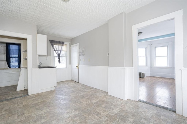 unfurnished room with an ornate ceiling, a sink, and wainscoting