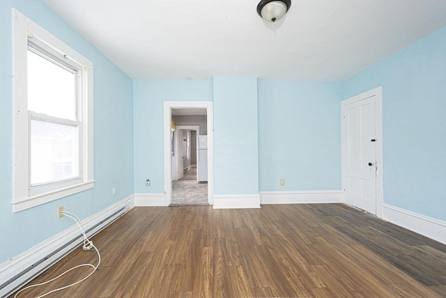 empty room featuring a baseboard radiator, dark wood finished floors, and baseboards