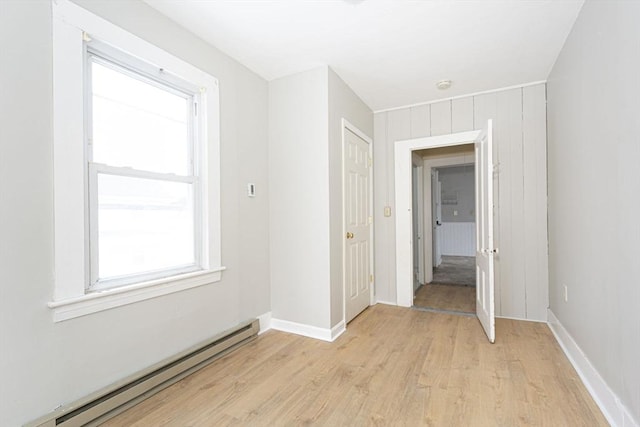 empty room featuring light wood-style floors, baseboards, and baseboard heating