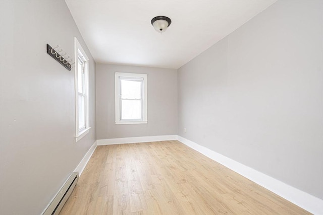 unfurnished room with light wood-style floors, baseboard heating, and baseboards