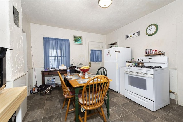 kitchen featuring white appliances, stone finish flooring, and a textured ceiling