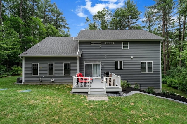 rear view of house with a shingled roof, a lawn, and a wooden deck