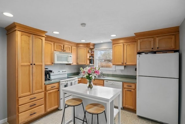 kitchen featuring a breakfast bar area, white appliances, a sink, light countertops, and decorative backsplash