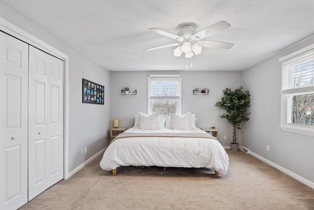 carpeted bedroom featuring a ceiling fan, a closet, multiple windows, and baseboards