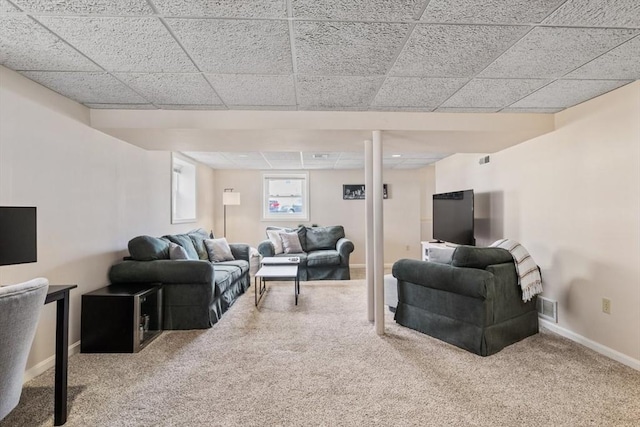 carpeted living area featuring a drop ceiling, visible vents, and baseboards