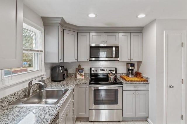 kitchen featuring recessed lighting, a sink, appliances with stainless steel finishes, gray cabinets, and tasteful backsplash