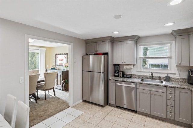 kitchen featuring decorative backsplash, stainless steel appliances, a sink, and gray cabinetry