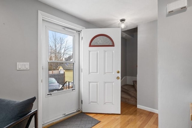 entryway featuring light wood-type flooring, baseboards, and stairs