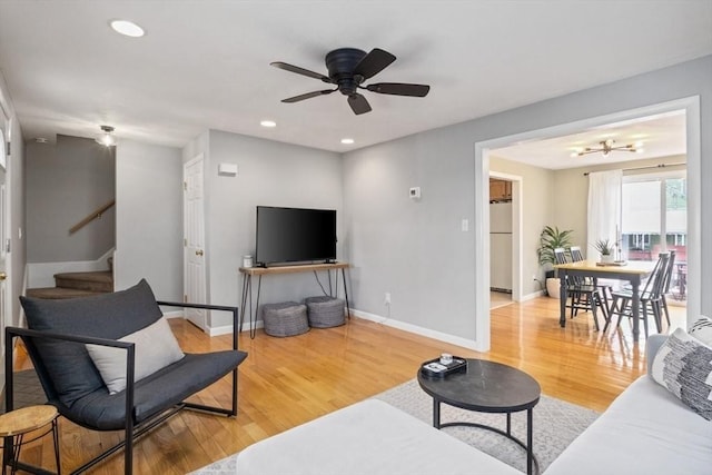 living area with light wood-style floors, baseboards, and stairs