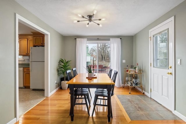 dining room featuring light wood-type flooring, baseboards, and an inviting chandelier