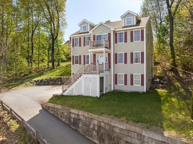 view of front facade featuring stairs, a front lawn, and a balcony