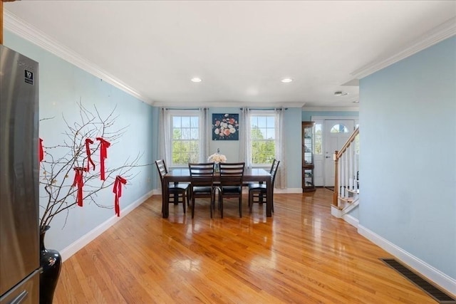 dining area with crown molding, baseboards, visible vents, and light wood-style floors