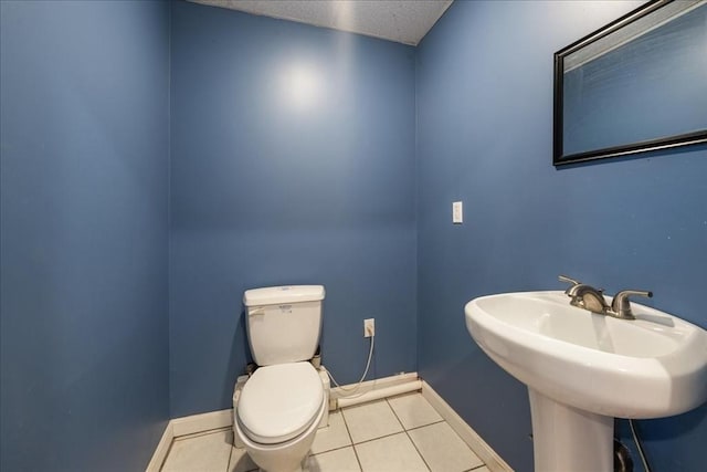 bathroom with a textured ceiling, a sink, tile patterned floors, baseboards, and toilet