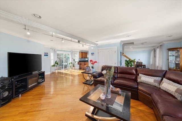 living room with crown molding, baseboards, track lighting, and light wood-type flooring