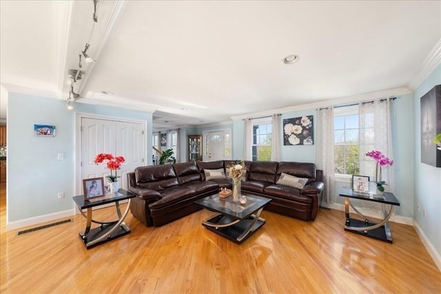 living area featuring baseboards, visible vents, ornamental molding, and light wood-style flooring