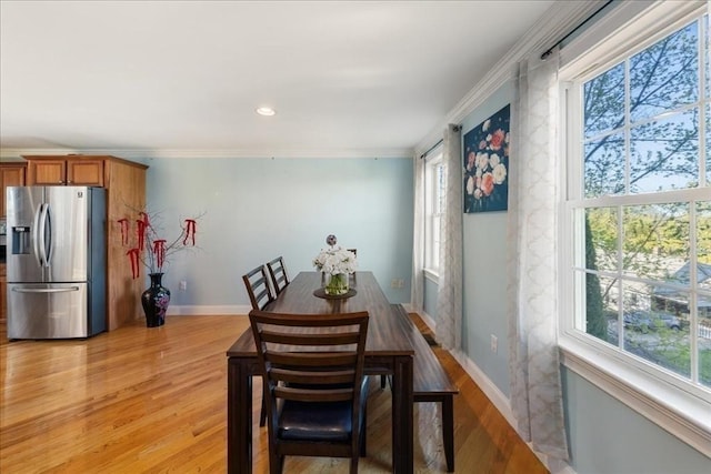 dining area with crown molding, baseboards, and light wood finished floors