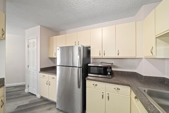 kitchen with stainless steel appliances, cream cabinets, and dark countertops