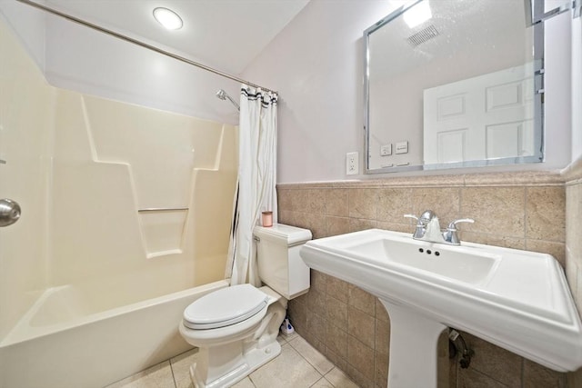 full bathroom featuring tile walls, visible vents, toilet, a sink, and tile patterned flooring