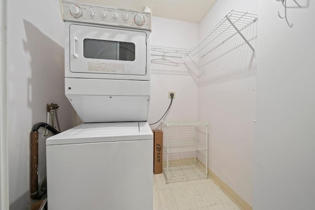 laundry room featuring laundry area, stacked washer and clothes dryer, baseboards, and light floors