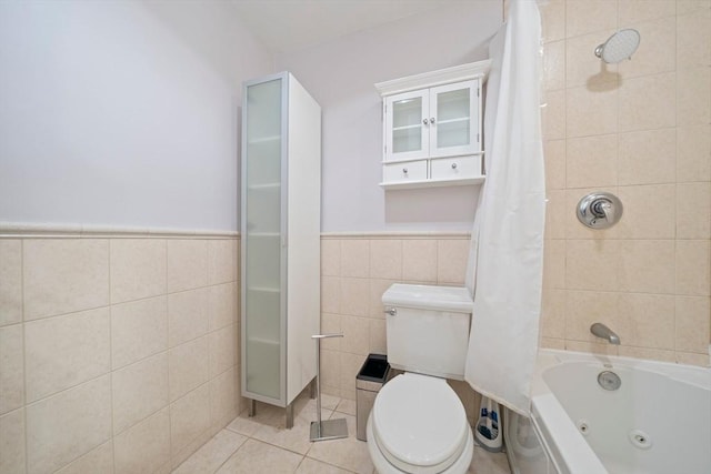 bathroom featuring toilet, a wainscoted wall, tile walls, a combined bath / shower with jetted tub, and tile patterned floors