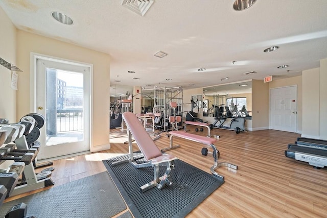 workout area with baseboards, visible vents, and wood finished floors