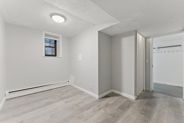 57 Brighton Ave Unit A, Boston, MA 02134 - below grade area with baseboard heating, wood finished floors, baseboards, and a textured ceiling