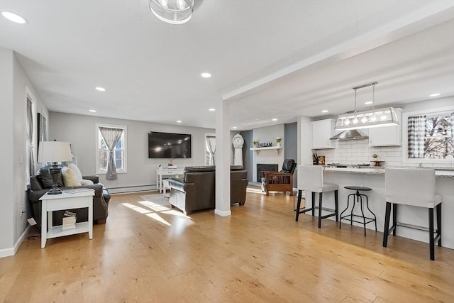 living room featuring light hardwood / wood-style flooring, a baseboard radiator, and a fireplace