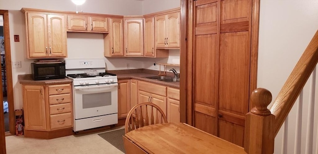 kitchen featuring white gas stove, a sink, black microwave, and light brown cabinets