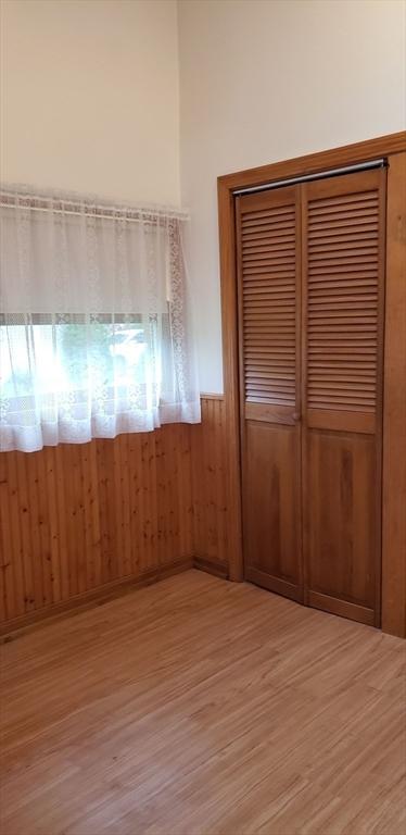unfurnished room featuring light wood-type flooring, wainscoting, and wood walls