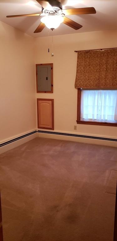 carpeted spare room featuring electric panel and ceiling fan
