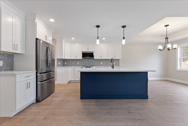 kitchen with white cabinets, stainless steel appliances, light hardwood / wood-style floors, and tasteful backsplash