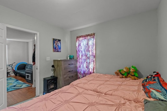 bedroom with a wood stove and wood-type flooring