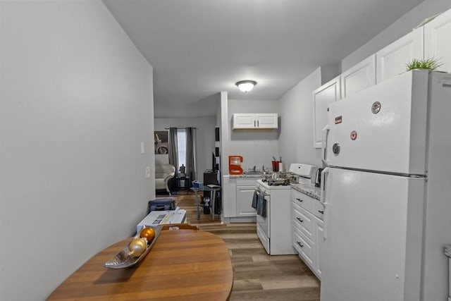 kitchen featuring white cabinetry, light stone countertops, white appliances, and light wood-type flooring