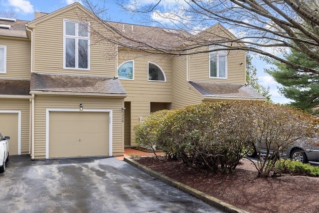 multi unit property with an attached garage, roof with shingles, and driveway