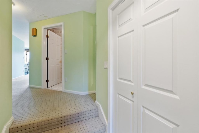 hall featuring light carpet and baseboards