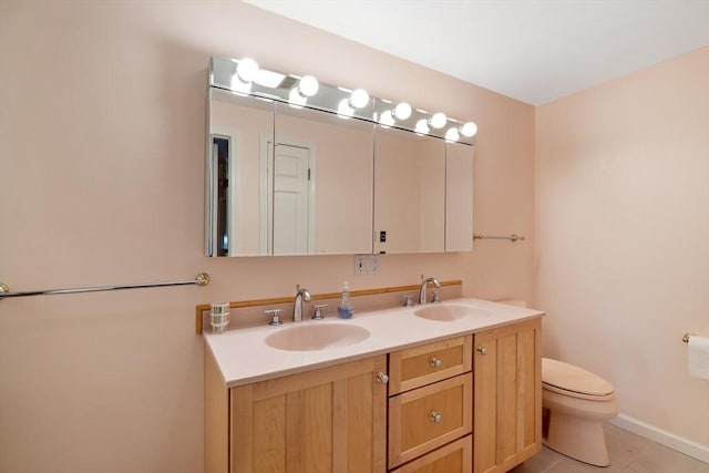 bathroom featuring double vanity, toilet, tile patterned floors, and baseboards