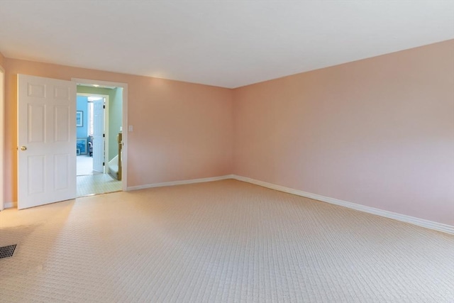 spare room with baseboards and light colored carpet