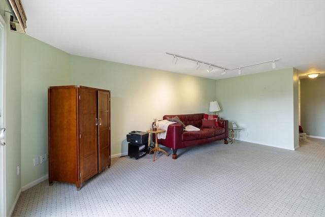 sitting room featuring rail lighting, light colored carpet, and baseboards