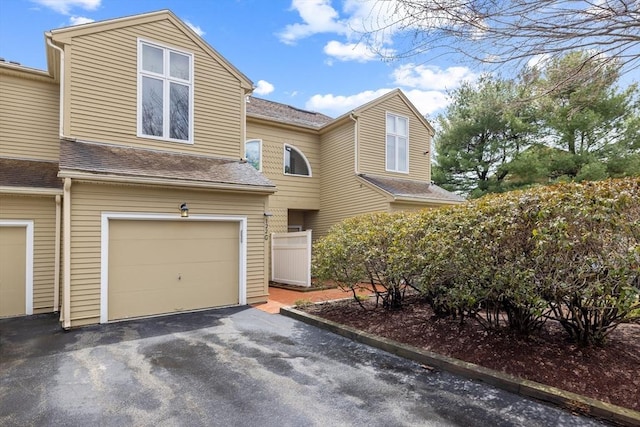 view of front of property with an attached garage, driveway, and roof with shingles
